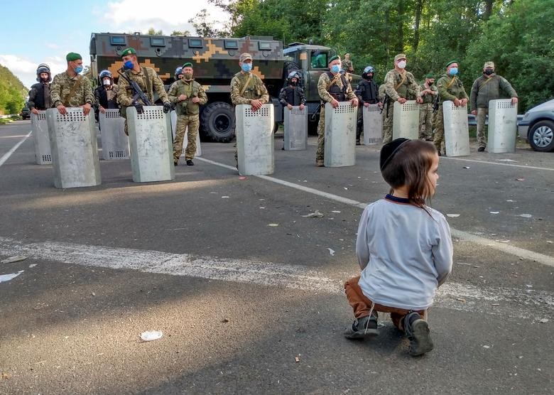 A Jewish pilgrim, who plans to enter Ukraine for a pilgrimage from the territory of Belarus, sits in front of Ukrainian service members near Novi Yarylovychi crossing point in Chernihiv Region, Ukraine.  BelaPAN via REUTERS